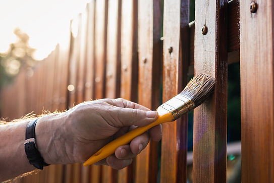 Paint wood stain Painting protective varnish on wooden picket fence at backyard.jpg