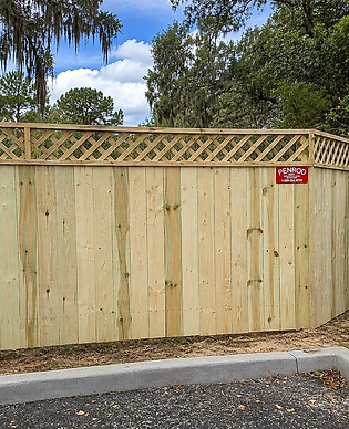 Tall wood privacy fence with lattice top installed at a commercial property in North Central Florida — built by Penrod Lumber & Fence