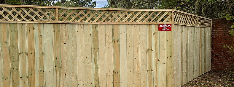 Tall wood privacy fence with lattice top installed at a commercial property in Ocala, Florida — built by Penrod Lumber & Fence