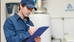 man in blue overalls and cap with a clipboard