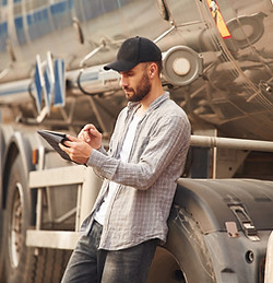 man on tablet next to oil tank truck