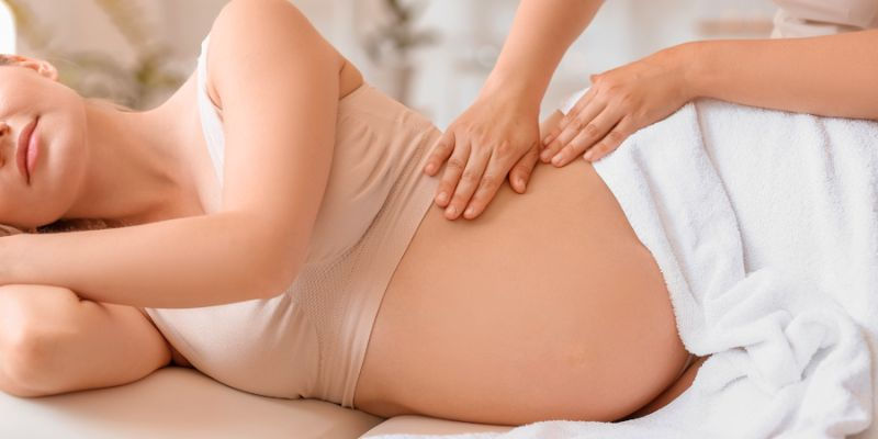 Pregnant woman receiving a gentle abdominal massage in a relaxing spa setting