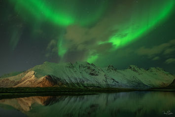 Grüne Polarlichter über schneebedeckten Bergen in Skandinavien.