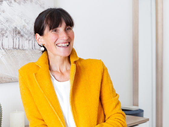 Lächelnde Unternehmerin im gelben Blazer bei einem authentischen Personal-Branding-Shooting in heller und moderner Umgebung.