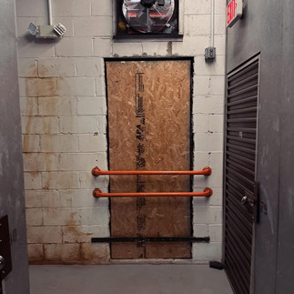 Interior view of a hallway in a commercial building with a window opening boarded up with plywood.