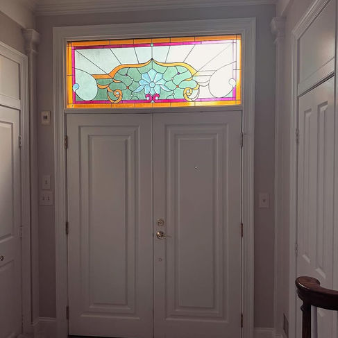 Interior view showing colorful stained glass transom above white double entry doors in Potomac, MD home.