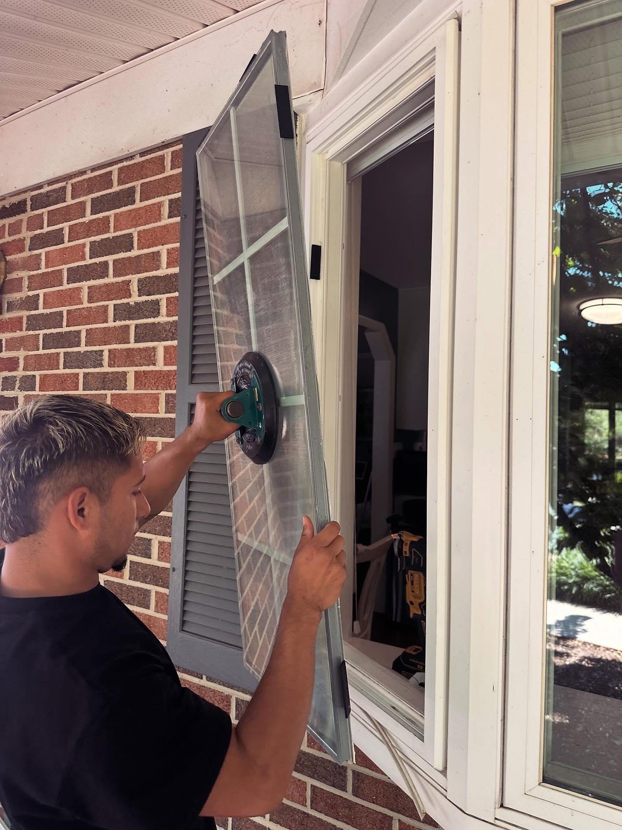 Technician removing the old window glass using a suction cup tool during the replacement process.