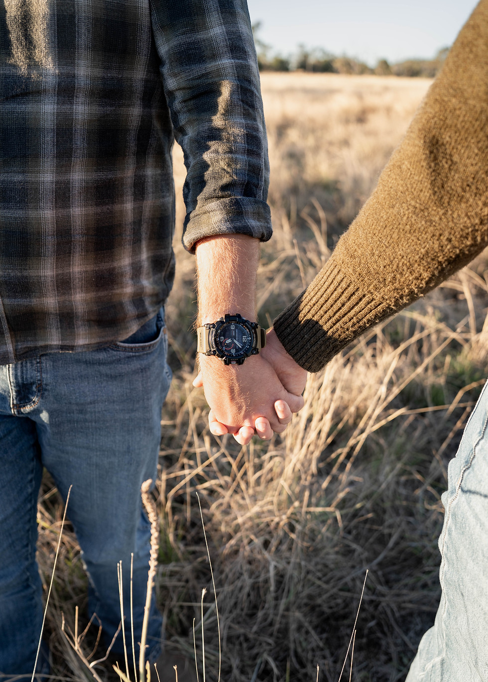 Close-up of a couple holding hands in a sunlit field during a countryside photography session by Barefoot Ember