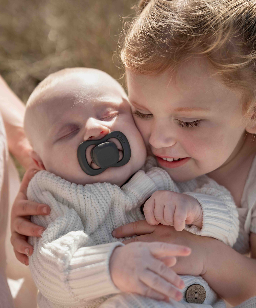 Older sibling cuddling baby during a family photography session, capturing warmth and genuine connection