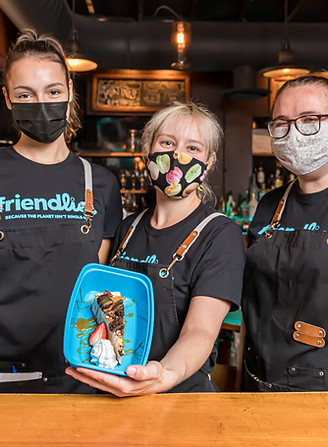 Restaurant employees in Friendlier apparel, showing off a cheesecake in a Friendlier container