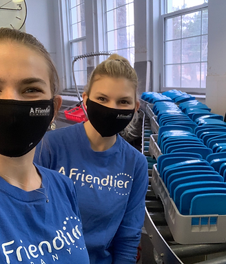 Friendlier employees beside trays of reusable containers getting washed