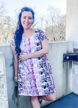 Lindsey of Inside The Hem standing in front of a cement wall in a colorful dress.