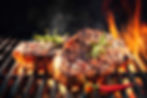Beef steaks sizzling on the grill with flames.jpg