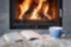 Open book, cup of tea and warm plaid near burning fireplace. Hygge concept.jpg