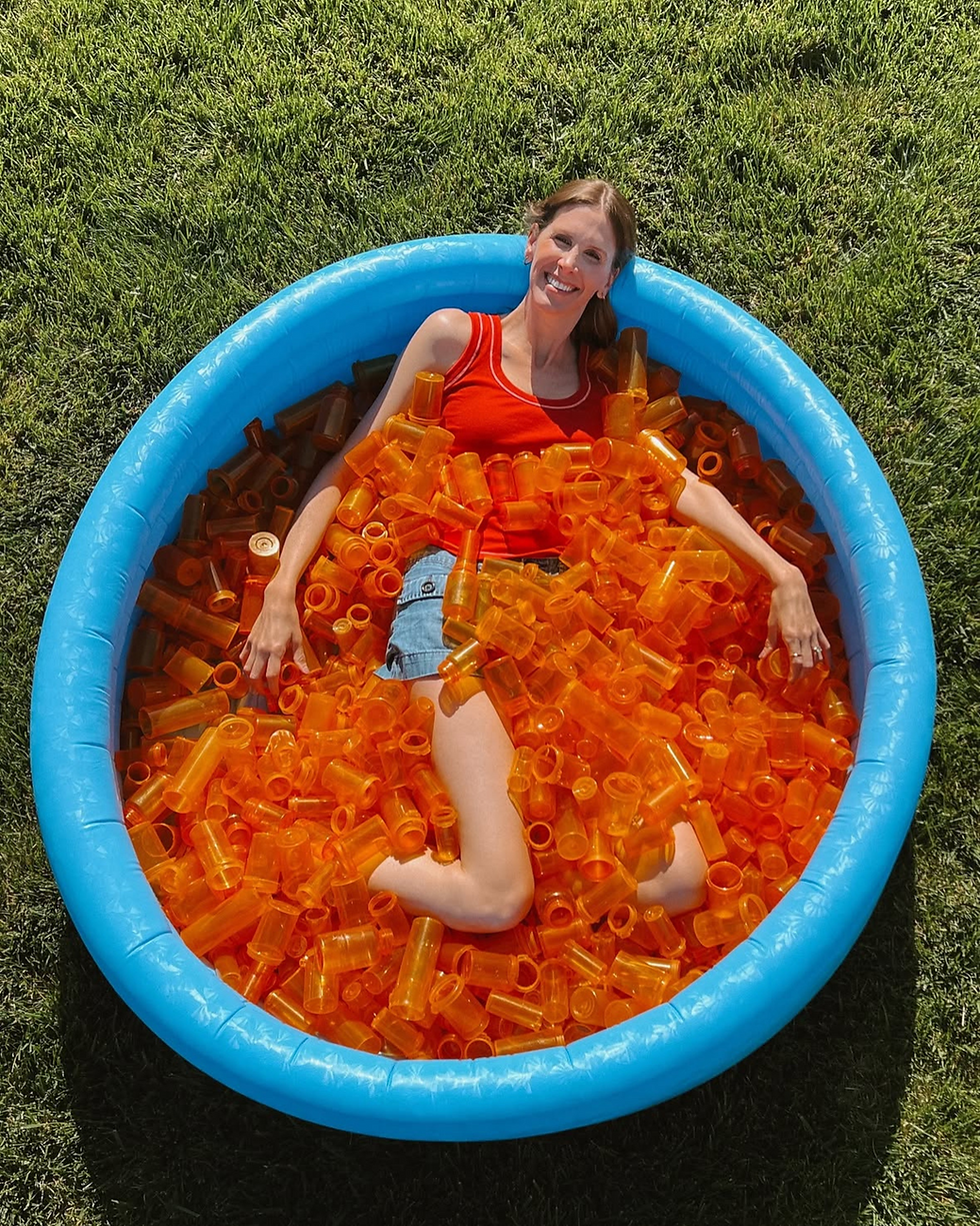 Founder Claire Ring poses in a kiddie pool filled with empty plastic pill bottles                                                            Source: Cocoplum Instagram