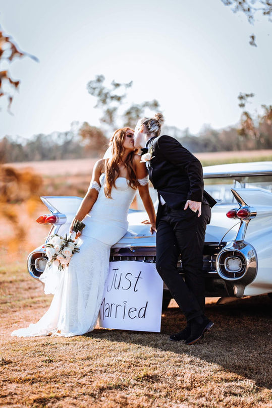 Just married couple embracing next to the Cadillac DeVille 