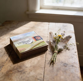 Bundle of woodland bird cards on a table with a and picked bunch of flowers and feathers