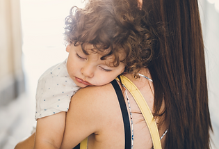Toddler falling asleep in their mother's arms due to overtirednes