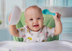 Baby exploring self-feeding with a spoon during the introduction of solid foods