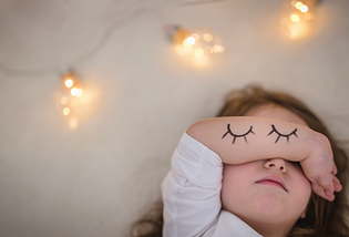 Overtired toddler sleeping with an arm covering their eyes