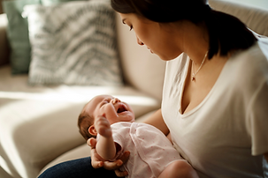 Crying baby being comforted in their mother's arms during the evening witching hour