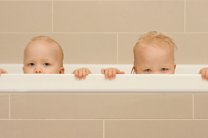 Twin babies during bath time as part of a predictable bedtime routine that supports healthy sleep habits