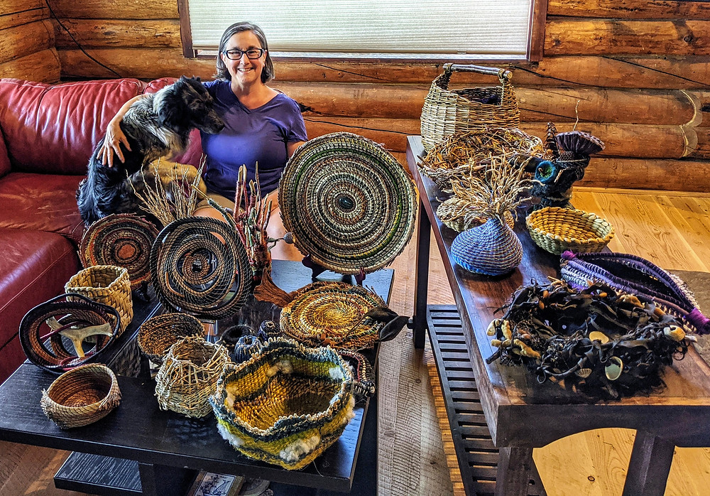 This is a picture of Lisa with her dog, Tazzie. They are sitting on a red couch behind a bunch of hand made baskets in natural blueish tones.