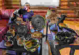 This is a picture of Lisa with her dog, Tazzie. They are sitting on a red couch behind a bunch of hand made baskets in natural blueish tones.