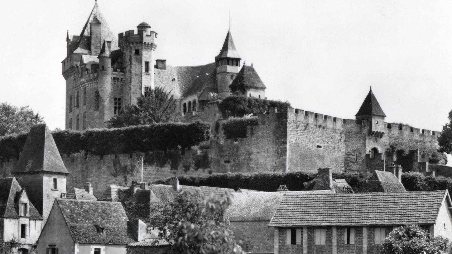 Vieux château fortifié, bâtiments en pierre et végétation luxuriante, Vitrac en Périgord, France.