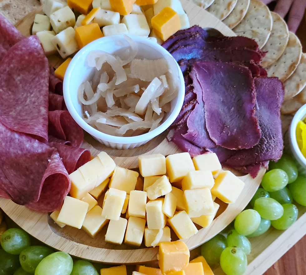 Sliced smoked meat with spices on a wooden board, garnished with rosemary. Warm, rustic setting with blurred greenery in the background.