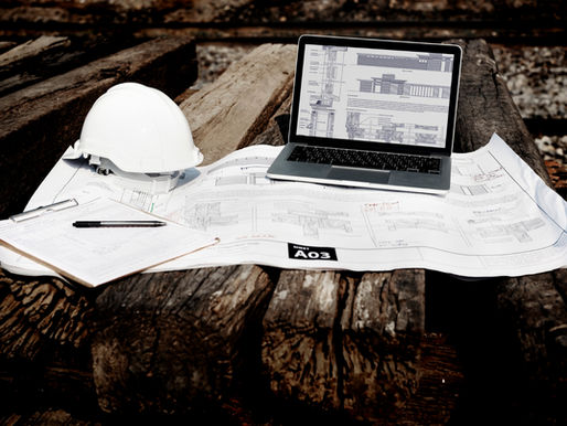 Planos de obra, casco y herramientas de medición sobre un escritorio de ingeniería