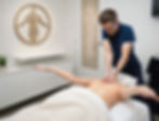 Person relaxing in a minimalist wellness studio with soft ambient lighting and organic textures