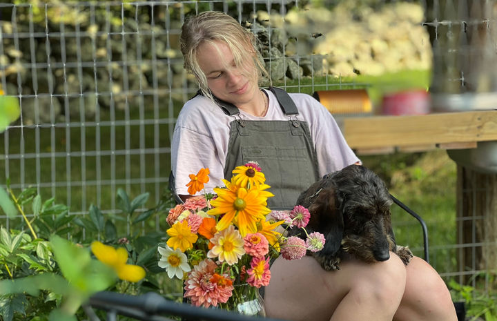 Margit Burgess, owner of Wild Roots Design, sitting with her dog and a bouquet of flowers