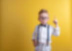 Portrait of stylish little boy with finger pointed up. Little child in glasses has idea. K