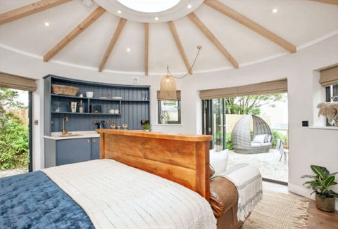 This elegant eco roundhouse suite boasts a thoughtfully designed kitchenette and an open-plan layout, ideal for a peaceful countryside escape. With natural light streaming in from the skylight and wide bi-fold doors, it offers a seamless blend of indoor comfort and outdoor relaxation, perfect for eco-conscious travellers.