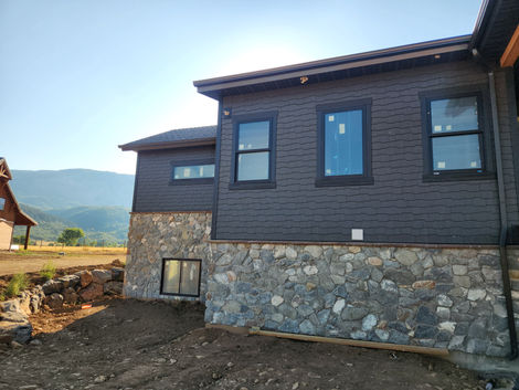 a house with a stone wall and a dark grey shaker siding