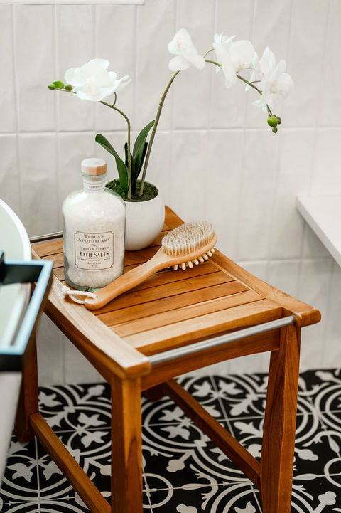 a wooden stool with a bottle of bath salts and a brush on it