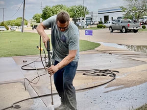 Worker pressure washing a concrete driveway – Good Deal Builder, Dallas TX