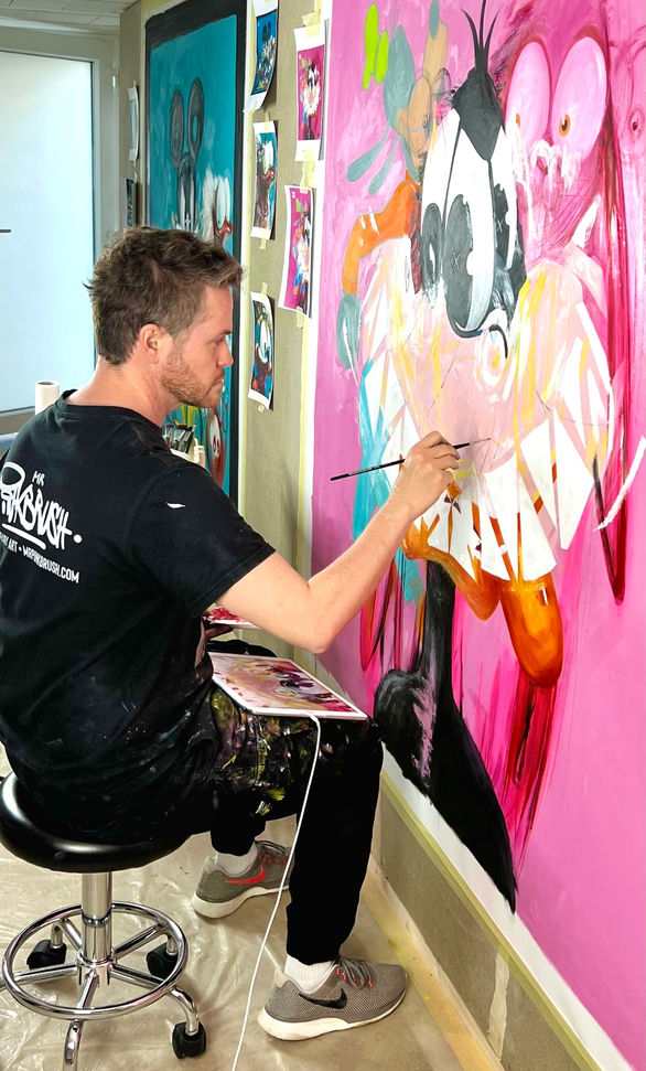 The artist Mr. Pinkbrush in his studio on a colorful cartoon painting on canvas_www.mrpinkbrush.com