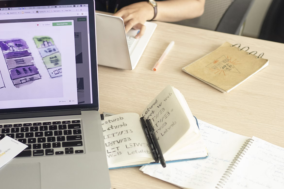 A person organizing study notes and diagrams on a desk with a laptop