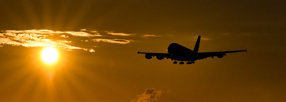 An airplane is flying into the sunset.
