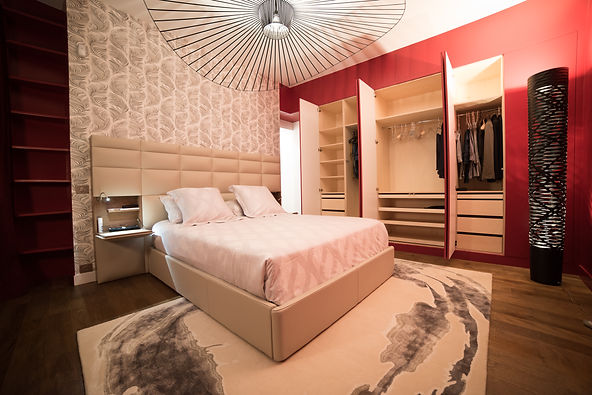 Une chambre rouge et beige. Rénovation d'un appartement haussmannien de 160m2 à Paris 1er. Tête de lit papier-peint, cuir, tapis, lit king size, dressing sur mesure bouleau, suspension vertigo, parquet chêne. Design Morgane Coroller