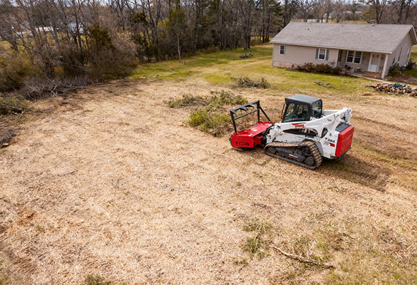 Bobcat clearing the land near a house; residential property clearing Timberland Forestry