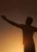 Man silhouetted at sunset, arms outstretched