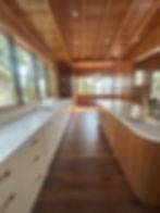 Eye-level view of a bright kitchen with large windows and white cabinets