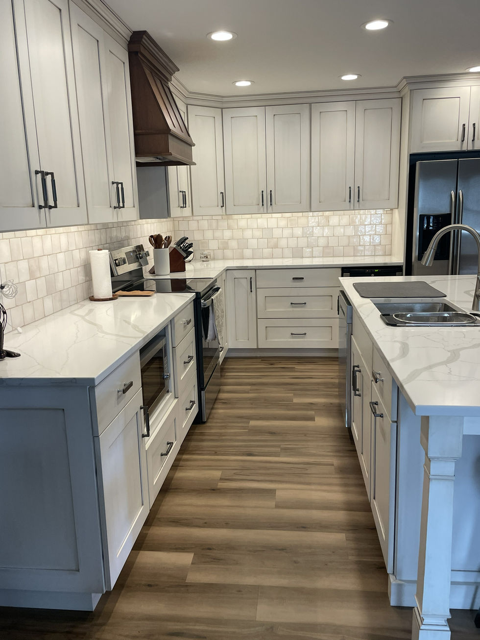 Modern kitchen with white cabinets and wooden floor.