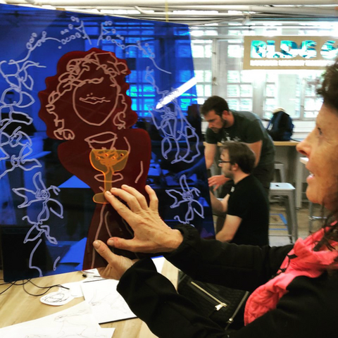 woman touches etched blue and red acrylic sheets held up to light