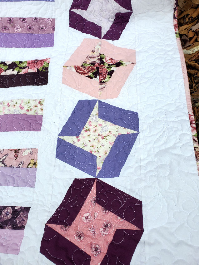 close-up of striped and friendship stars quilt in purples, pinks and whites