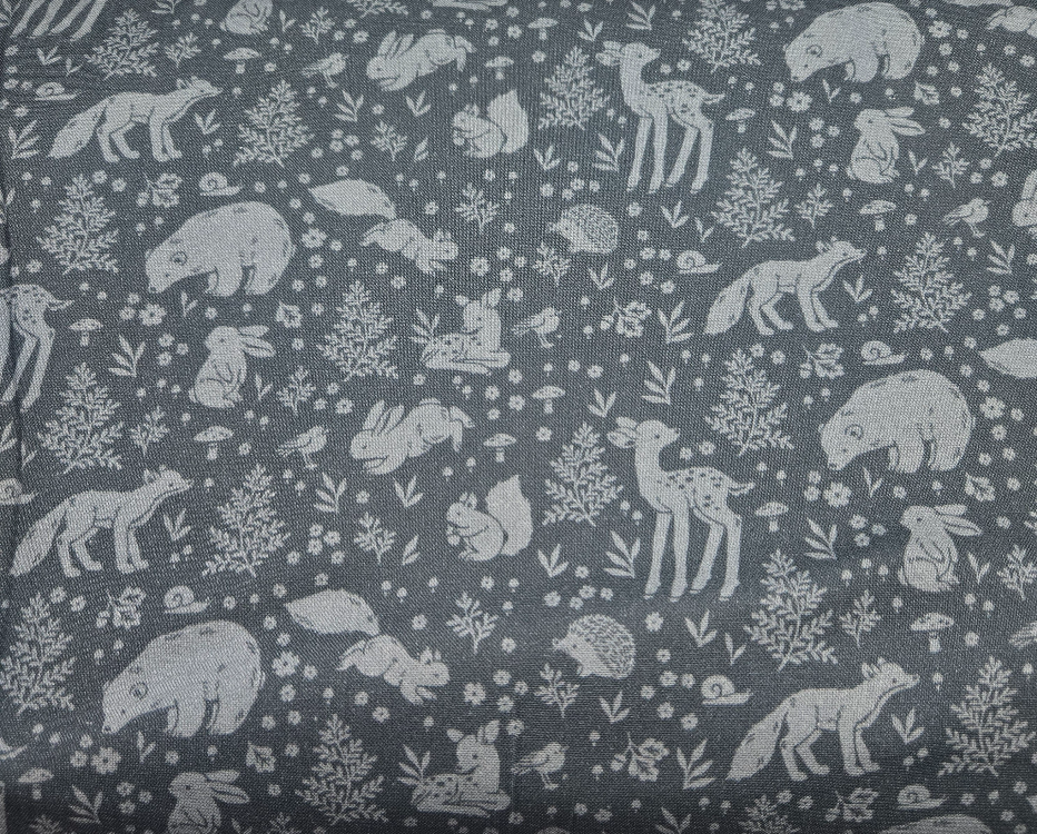 Iron colored fabric hosting whimsical woodland prints featuring cute animals, mushrooms, and lush greenery