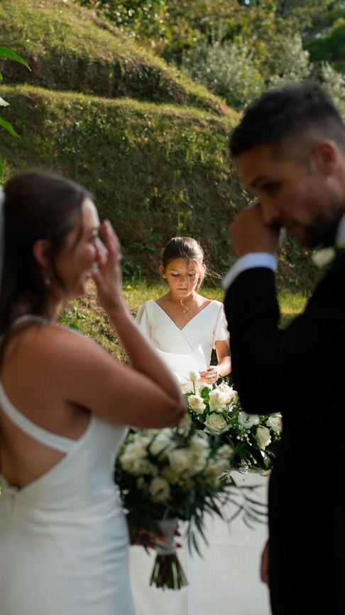 Bride smiling as the groom gently lifts her veil, tender moment filled with emotion.